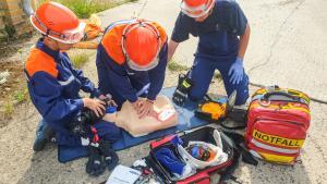 Zwei Mitglieder der Jugendfeuerwehr üben die Reanimation an einem Übungstorso mit Defibrillator (AED) und Beatmungsbeutel.