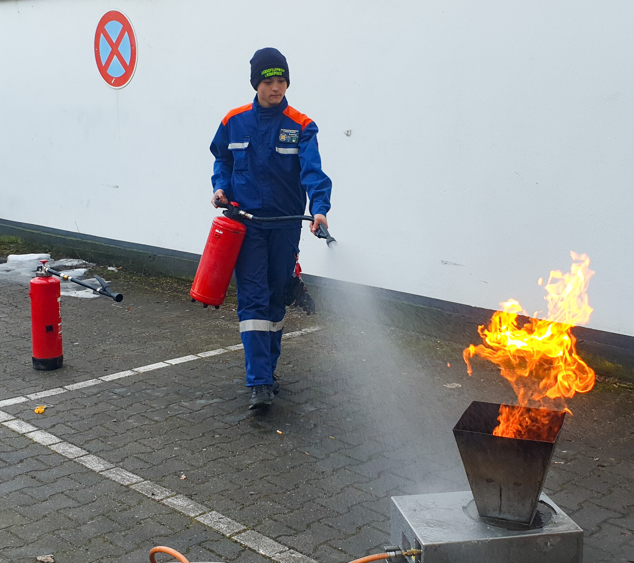 Ein Mitglied der Jugendfeuerwehr trainiert den sicheren Umgang mit dem Feuerlöscher an einem gasbetriebenen Feuerlöschtrainer.
